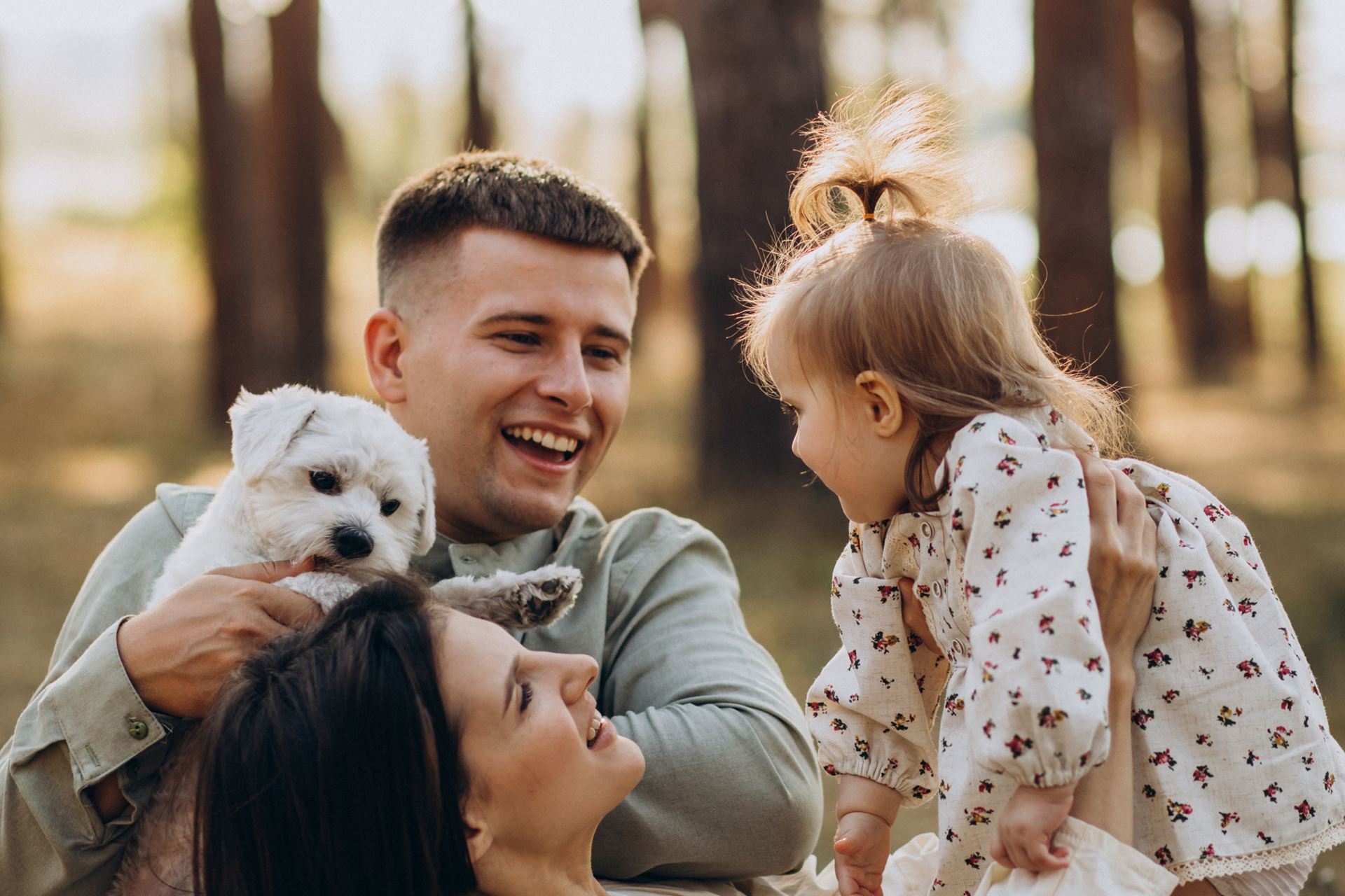 Familia joven jugando con su hija y su mascota al aire libre